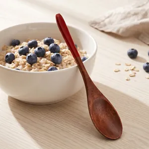 Handcrafted dark wood stirring spoon with red handle tip for coffee dessert and honey