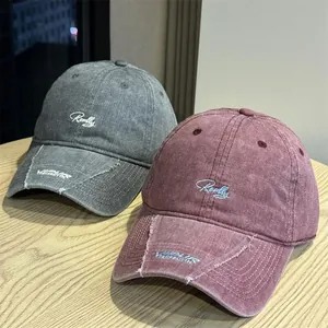 Detalle de gorras de béisbol vintage lavadas con bordado en gris y color burdeos.