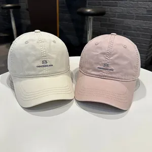Primo piano di due cappellini da baseball in stile coreano beige e rosa ricamati