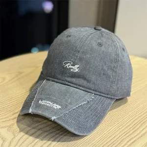 Primer plano detallado de una gorra de béisbol gris desgastada vintage con bordado en cursiva blanca