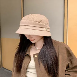 Detailed view of an Asian woman wearing a stylish camel knitted bucket hat in a minimal setting.