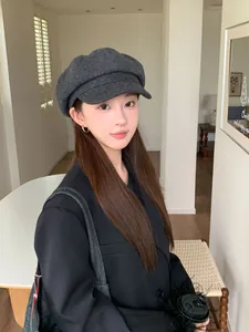 Elegant dark grey wool newsboy hat worn by a model in a stylish indoor setting
