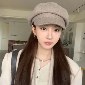 Classic British style solid beige newsboy cap for women worn by a model in a room