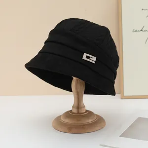 Detailed view of a black Korean-style bucket hat with a pleated band and metallic buckle.