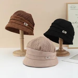 Detail view of knitted suede winter bucket hats in three classic colors on wooden stands
