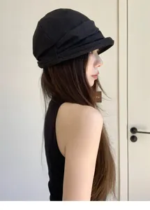Side view of a stylish black pleated bucket hat worn by an Asian model in profile