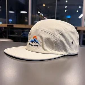 Dettaglio ravvicinato di un cappello 5-panel beige a rapida asciugatura con ricamo