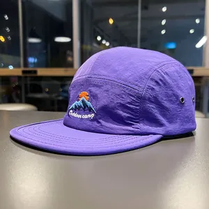 Dettaglio ravvicinato di un cappello a cinque pannelli viola con ricamo di montagna
