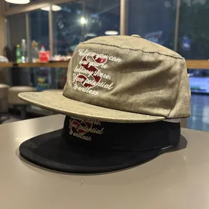 Close-up of embroidered motivational quotes on khaki and black flat brim hats