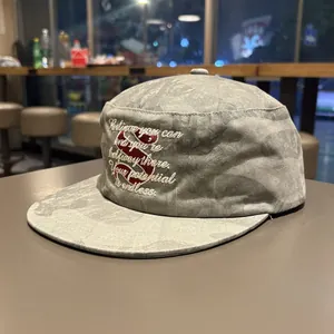 Close-up of grey washed flat top cadet cap with motivational embroidery