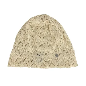 Dettaglio berretto in maglia a uncinetto traforato beige con motivo floreale retrò