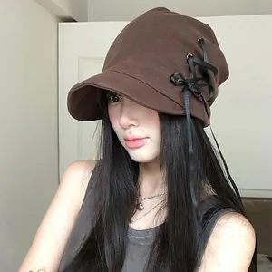 Cappello a secchiello marrone con lacci in nastro nero indossato da modella asiatica