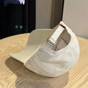 Detalle de la hebilla metálica ajustable en la correa de una gorra de béisbol beige