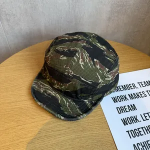 Vista dettagliata di un cappello 5-panel mimetico tiger stripe su legno.