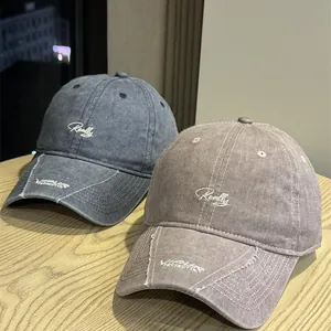 Gorras de béisbol vintage lavadas con bordado sobre una mesa de madera natural.
