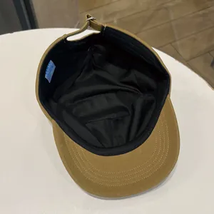 Close-up showing the black lining and label of a khaki cotton flat top military cap