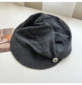 Close-up of retro grey newsboy cap with pleated fabric and silver heart button.