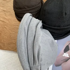 Close-up detail showing the soft pleated texture of stylish beanie hats in grey black and brown