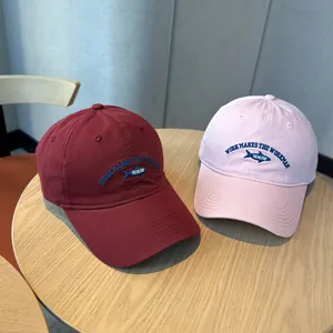 Close-up of embroidered fish logo on vintage washed burgundy and pink baseball caps