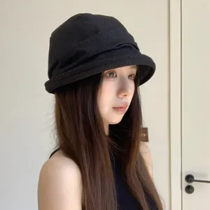 Stylish black pleated bucket hat for women featured in a minimalist casual indoor setting