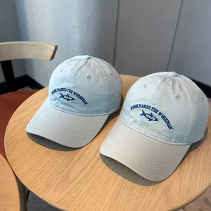 Detailed macro view of embroidered fish logo on washed cotton baseball caps in soft colors