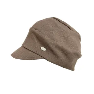 Side view of a vintage brown knitted newsboy cap with a small metal logo detail