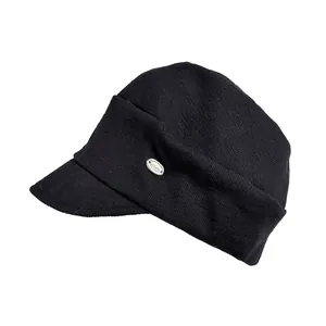 Close-up side view of a black knitted equestrian hat with a small metal logo detail.