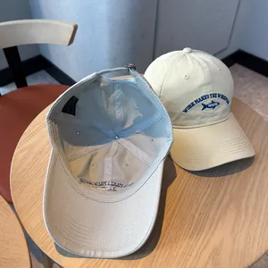 Detail of a washed cotton baseball cap showing fish embroidery and interior lining.