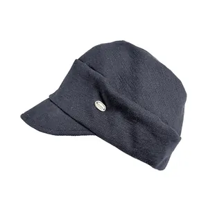 Close-up detail view of a vintage dark grey knit newsboy cap with an elegant metal tag.