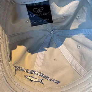 Detail view of the interior woven label and embroidery on a washed beige baseball cap.