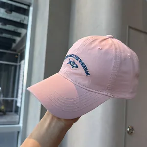 Detailed macro view of pink washed cotton baseball cap featuring blue fish embroidery design