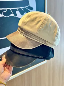 Close-up showing texture of suede newsboy caps with PU leather brim in beige and black