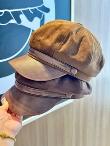Detail view of two brown suede newsboy hats with PU leather brims for women's autumn style.