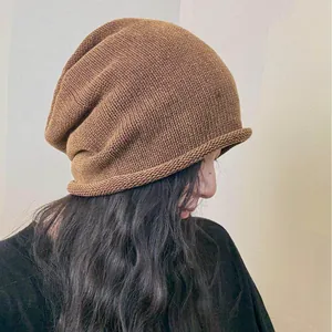 Berretto in maglia marrone mélange alla moda con bordo arrotolato indossato da modella