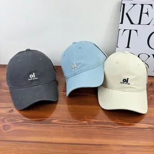Close-up detail of embroidered 'oi' baseball caps in grey, light blue, and cream colors