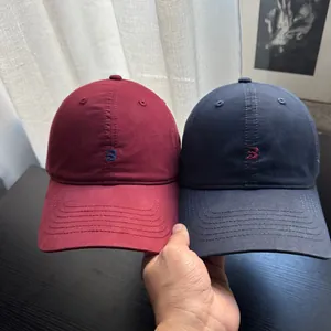 Detailansicht von burgunderfarbenen und marineblauen Baseballkappen mit B-Stickerei
