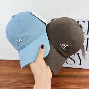 Detail shot of trendy embroidered 'oi look at me' baseball caps in blue and brown fabric