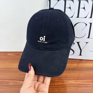Close-up detail of a navy blue embroidery baseball cap with "oi look at me" text design.
