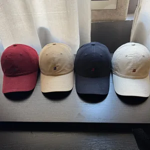 Detailansicht von vier farbigen Baseballkappen mit Stickerei auf dunklem Holz-Hintergrund