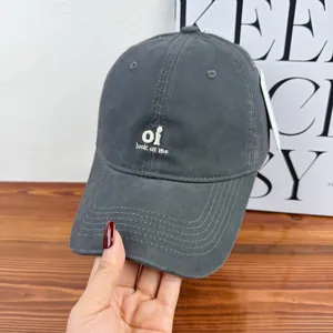 Detailed macro view of embroidered grey washed cotton baseball cap being held by a hand