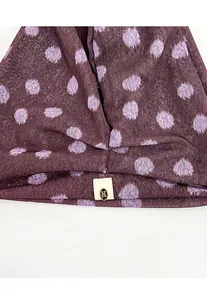 Close-up of thin polka dot slouchy beanie with small decorative metal 'K' tag