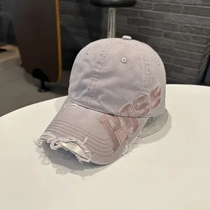 Gros plan d'une casquette en coton lavé vintage avec broderie ROSE et bords effilochés