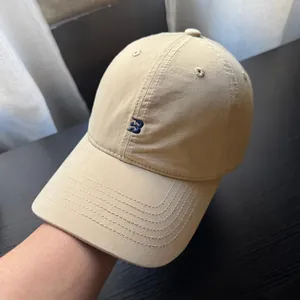 Detailansicht der khakifarbenen Baseballkappe mit blau besticktem Buchstaben B-Logo