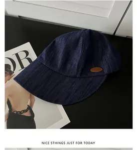 Vue détaillée d'une casquette de baseball texturée bleu marine de style denim sur fond noir.