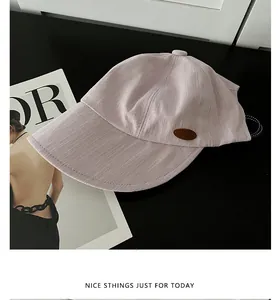 Vue détaillée d'une casquette de baseball rose avec écusson en cuir sur fond noir.
