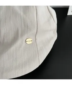 Gros plan du logo de marque doré sur un béret en sergé beige pour femmes élégantes