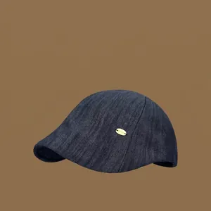 Casquette plate vintage en denim bleu foncé avec petit détail en métal doré pour femme