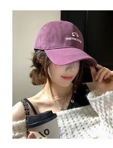 Nahaufnahme einer lila bestickten Baseballkappe, getragen von einem asiatischen Modell mit Kaffee