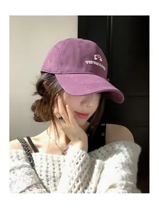 Detail einer lila bestickten Baseballkappe, getragen von einem asiatischen Modell.