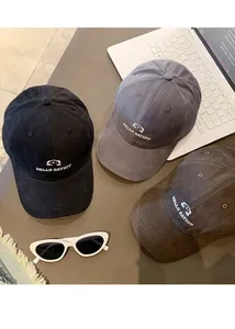 Detailansicht von drei bestickten Baseballkappen in Schwarz, Grau und Braun.